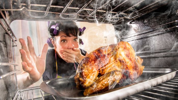 Shocked lady opens oven door to smoking chicken