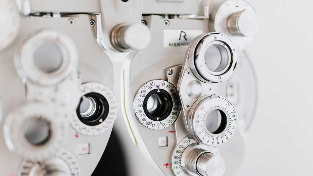 Close-up of an optometry phoropter machine used for eye exams and vision testing with adjustable lenses and dials.